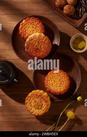 Blick von oben auf einige traditionelle Mondkuchen auf runden Holzgerichten. Ein Gericht mit Walnüssen und Sonnenblumenkernen. Traditionelles chinesisches Festival Stockfoto