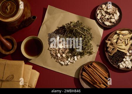 Getrocknete Minze, Poria cocos, Ingwer, Lavendel und Nelken auf Papier. Irdener Topf, eine Schüssel Tonic mit einigen Holzgeschirr, die enthält Stockfoto