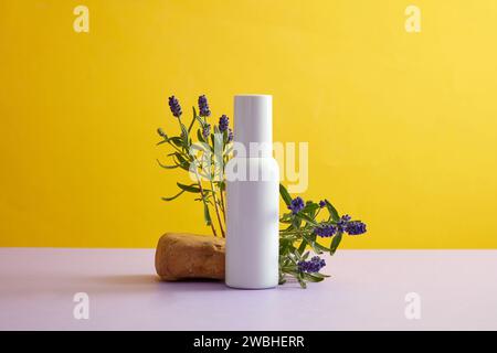 Minimalistische Szene für Werbung für Kosmetik mit weißer Flasche ohne Marke, dargestellt auf gelbem Hintergrund mit blühender Blume und kleinem Felsen. Vorderansicht, Stockfoto