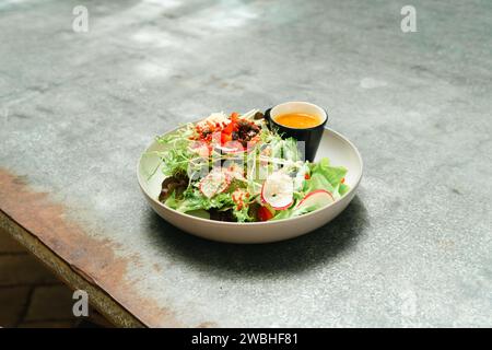 Frischer grüner veganer Salat aus grünen Blättern und Gemüse. Draufsicht auf grauem Steintisch. Griechischer Salat mit frischer Gurke, Tomate, süßem Pfeffer, Lettu Stockfoto