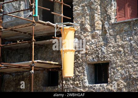 Rutsche gelb zur Entfernung von Schutt an der Gebäudefassade bei Renovierung Baustelle in der Straße Stockfoto