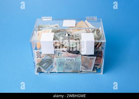 Wohltätigkeits- und Geldgeld CZK tschechische Kronen-Banknoten in einer transparenten Spendenbox für Geldspenden. Eine finanzielle Unterstützung, sammelt Geld. Der Akt des Gebens Stockfoto