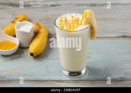 Milch mit Honig und Banane im Glas auf Holztisch Stockfoto