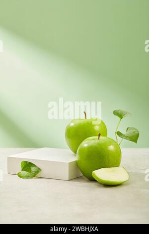 Quadratisches Podium mit leerem Platz, mit grünen Äpfeln aus biologischem Anbau. Das Essen von grünem Apfel (Malus domestica) hat sich gezeigt, um die Gesundheit des Herzens zu verbessern Stockfoto