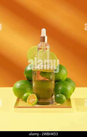 Tropfflasche ohne Marke auf Glaspodium in zylinderförmiger Form mit Limetten und Kumquats umgeben. Leeres Etikett für kosmetische Produktmodelle von Li Stockfoto