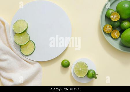 Heller Hintergrund mit Podesten in rundem, weißem Handtuch und einer Schale aus Kumquat und Limette. Freie Fläche für Kosmetikwerbung von Lime und Stockfoto
