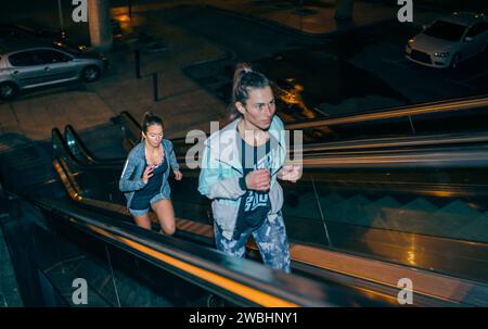 Freundinnen trainieren nachts die Rolltreppe hinauf in der Stadt Stockfoto