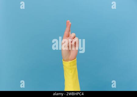 Nahaufnahme von weiblichen Händen, die mit gekreuzten Fingern beten, hofft auf ein wunderbares gutes Ergebnis, isoliert über blauem Studiohintergrund mit Kopierraum. Body langu Stockfoto