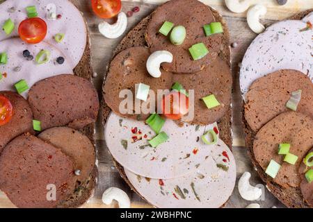 Dresden, Deutschland. Januar 2024. Brotscheiben mit verschiedenen veganen Würstchen liegen auf einem Holzbrett. Quelle: Sebastian Kahnert/dpa/Alamy Live News Stockfoto