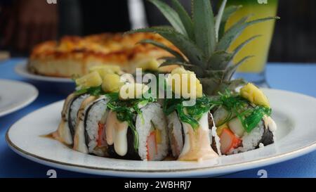 Koch bereitet japanische Gerichte zu. Japanischer Koch, der Sushi für Gäste zubereitet. Junger Koch serviert traditionelles japanisches Sushi mit Ananas Stockfoto