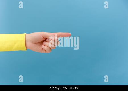 Nahaufnahme der weiblichen Hand, die auf den Kopierraum für Design zeigt, isoliert auf blauer Hintergrundwand im Studio. Werbestelle für Text-Bild-Werbung Stockfoto