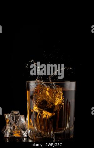 Glas Whiskey mit Spritzer auf schwarzem Hintergrund Stockfoto