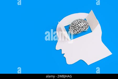Menschliche Kopf-Silhouette aus weißem Papier mit offenem Fenster, die einen faszinierenden Blick in die Feinheiten eines Stahlhirnmodells bietet. Aufgeschlossenes Denken Re Stockfoto