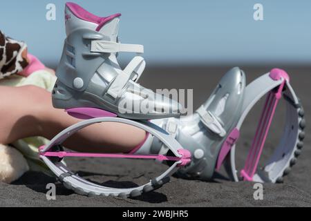 Nahaufnahme der pinken Kangoo-Sprungschuhe vor dem Fitness-Training im Freien, Aerobic-Training mit trendigen Sprungschuhen am Sandstrand Stockfoto