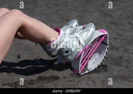 Nahaufnahme schlanke weibliche Beine im Sport Kangoo springt Stiefel am schwarzen Sandstrand vor Aerobic-Training im Freien, Fitness-Workout. Hochwinkelaufnahme Stockfoto