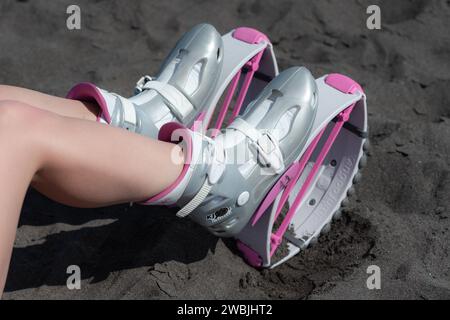 Hochwinkelschuss weibliche Beine im Sport Kangoo springt Schuhe auf schwarzem Sandstrand, bevor Outdoor-Aerobic-Training, Fitness-Workout Stockfoto