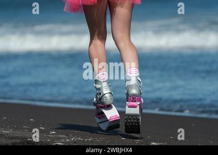 Sportliche Frauenbeine in rosa Sportschuhen Kangoo springt und kurzer Rock Laufen und Springen am Strand während des Trainings im Freien Stockfoto