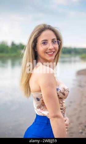 glückliche junge Frau mit Brille steht am Fluss *** glückliche junge Frau mit Brille steht am Fluss Stockfoto