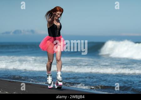 Weibliche Trainerin im Sport Kangoo springt Stiefel, schwarzer einteiliger Badeanzug und kurzer rosafarbener Rock beim Laufen und Springen Stockfoto