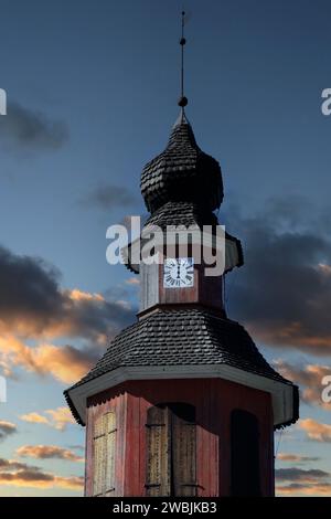 Glockenturm mit einer Handuhr gegen den Sonnenuntergang. Kirche St. Lawrence, Perniö, Salo, Finnland. Schwarzweißkonvertierung. Stockfoto