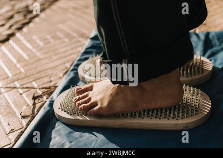 Füße stehen auf einem Sadhu-Brett (Yoga-Brett) mit scharfen Nägeln im Freien. Üben Sie Yoga, Meditation, Konzentration. Nahaufnahme. Stockfoto