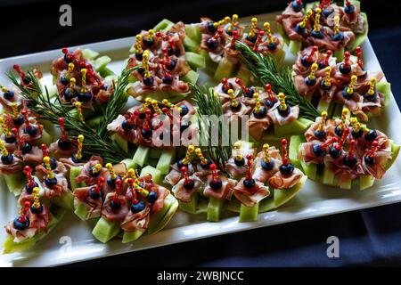 Eine Platte mit appetitlichen Vorspeisen mit bunten Spießen auf schwarzem Hintergrund Stockfoto