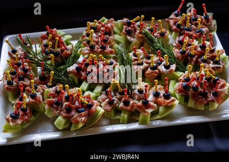 Eine Platte mit appetitlichen Vorspeisen mit bunten Spießen auf schwarzem Hintergrund Stockfoto