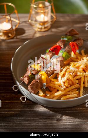 Eine vertikale Nahaufnahme von Fleisch auf einem Spieß mit Pommes frites Stockfoto