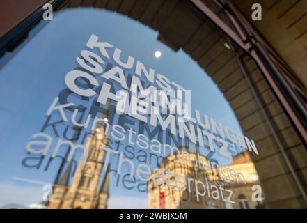 Chemnitz, Deutschland. Januar 2024. Die Kulisse des Theaterplatzes spiegelt sich in einer Scheibe der Kunstsammlungen Chemnitz wider. Die Museen der Kunstsammlungen haben nun ihren Ausblick auf das Jahr 2024 präsentiert. Zum Auftakt ist eine Ausstellung mit Fotografien aus der DDR dem Leben von vier Fotografinnen gewidmet. Die Kunstsammlungen werden seit Anfang des Jahres neu verwaltet. Florence Thurmes wird die Museen der Kunstsammlungen als Generaldirektor in das neue Ausstellungsjahr 2024 führen. Quelle: Hendrik Schmidt/dpa/Alamy Live News Stockfoto