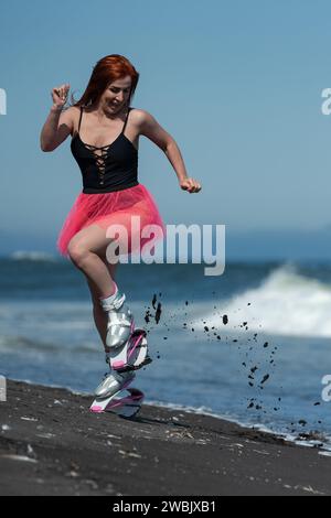 KAMTSCHATKA, RUSSLAND - 15. JUNI 2022: Frauen in Sportarten Kangoo springt Stiefel, schwarzer einteiliger Badeanzug und kurzer rosafarbener Rock laufen und springen auf schwarz Stockfoto