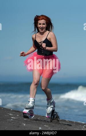 KAMTSCHATKA, RUSSLAND - 15. JUNI 2022: Sportliche Frau im Sport Kangoo springt Stiefel, schwarzer einteiliger Badeanzug und kurzer rosafarbener Rock Laufen und Springen auf b Stockfoto