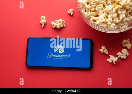 Nikolaev, Ukraine - 20. November 2021. In diesem Foto Popcorn und Illustration das Paramount Pictures Corporation Logo auf dem Smartphone auf rotem Hintergrund. Stockfoto