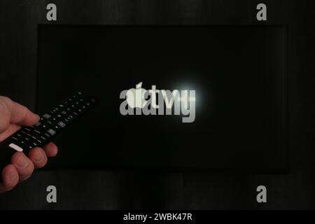 Nikolaev, Ukraine - 20. November 2021. Der Mann hält eine Fernbedienung mit dem neuen Apple TV-Bildschirm auf dem Fernseher. Draufsicht. Stockfoto