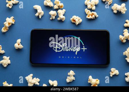 Nikolaev, Ukraine - 20. November 2021. Filme und Serien nach Abonnement, Konzept. Smartphone mit Disney Plus-Logo und Popcorn auf blauem Hintergrund. Bis Stockfoto