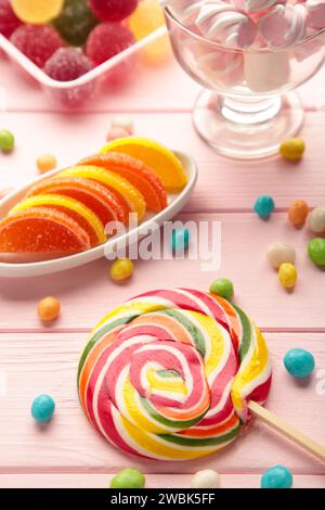 Bunte Bonbons Lutscher und Gelee auf rosafarbenem Hintergrund. Draufsicht. Vertikales Foto Stockfoto