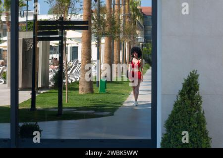 Brünette Mädchen mit flauschigen Haaren in Sportbekleidung Reflexion von Glas auf der Straße. Stockfoto