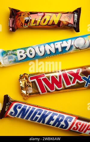 Snickers, Mars, Bounty und Twix Schokoladenriegel auf gelbem Hintergrund. Draufsicht. Nikolaev, Ukraine - 19. Dezember 2021 Stockfoto