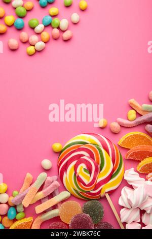 Bunte Bonbons Lutscher und Gelee auf rosafarbenem Hintergrund. Draufsicht. Vertikales Foto Stockfoto