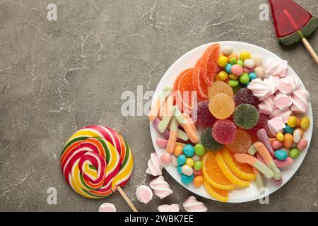 Bunte Bonbons Lutscher und Gelee auf grauem Hintergrund. Draufsicht. Vertikales Foto Stockfoto