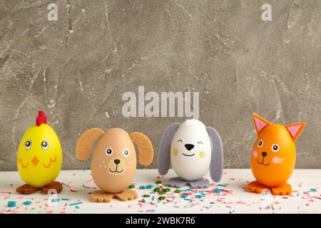 Osterferienkonzept mit niedlichen handgemachten Eiern, Hunden, Küken und Katzen auf grauem Hintergrund. Draufsicht. Frohe Ostern Stockfoto