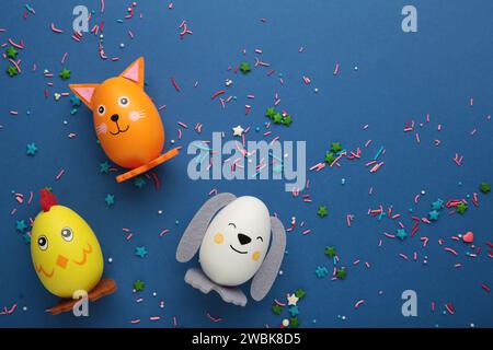 Osterferienkonzept mit niedlichen handgemachten Eiern, Hunden, Katzen und Küken auf blauem Hintergrund. Draufsicht. Stockfoto