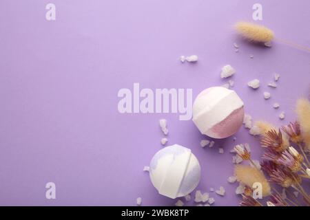 Komposition mit Badebomben, Meersalz, trockene Blumen auf lila Hintergrund mit Kopierraum Stockfoto