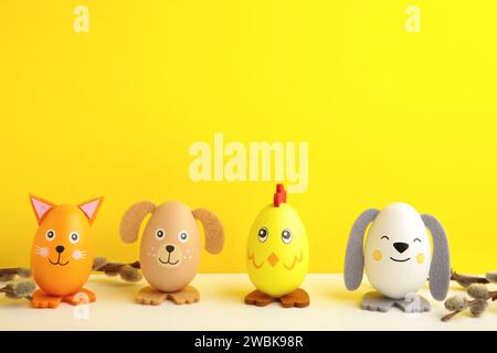 Osterferienkonzept mit niedlichen handgemachten Eiern, Hunden, Küken und Katze auf gelbem Hintergrund. Draufsicht. Frohe Ostern Stockfoto