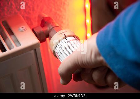 Hand auf den Thermostat eines Heizungssystems in einer Wohnung. Stockfoto