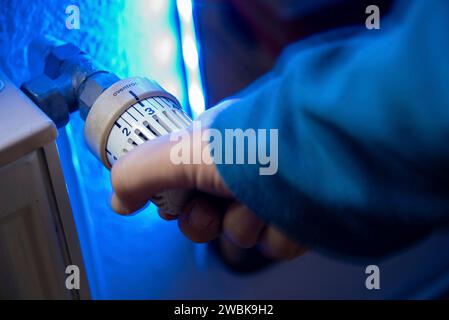 Hand auf den Thermostat eines Heizungssystems in einer Wohnung. Stockfoto