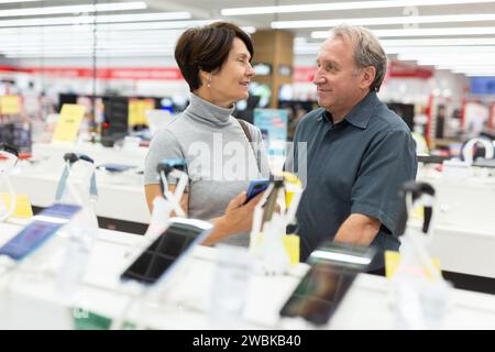 Reifes Ehepaar entscheidet sich fleißig für ein Smartphone im Supermarkt Stockfoto