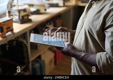 Seitenansicht Nahaufnahme eines Zimmermanns mit digitalem Tablet in der Werkstatt mit Holzbearbeitungsplänen auf dem Bildschirm Stockfoto