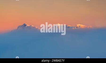 Schneebedeckte Berge im letzten Sonnenlicht aus der Wolkendecke, Brentenjoch und Zugspitze, Tirol, Österreich Stockfoto