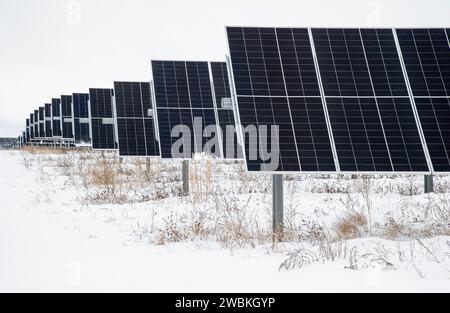 Der Rand von Reihen von Solarpaneelen, die landwirtschaftliche Felder ersetzt haben. Komplett von Schnee umgeben an einem grauen Wintertag im ländlichen Wisconsin. Stockfoto