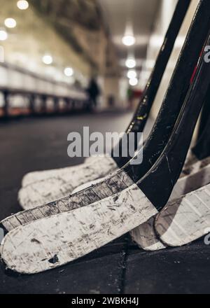 Hockeyschläger mit Klebeband, die sich an einer Wand an der Eislaufbahn beugen Stockfoto
